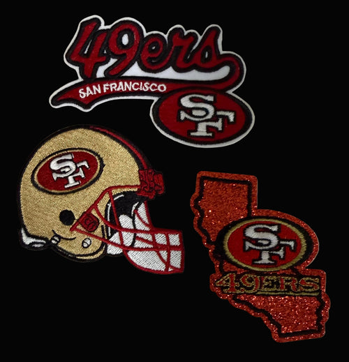 Three San Francisco 49ers embroidered patches on a white fabric background: a '49ers San Francisco' script patch, a football helmet patch, and a glittery California-shaped patch with '49ers' and the SF logo.